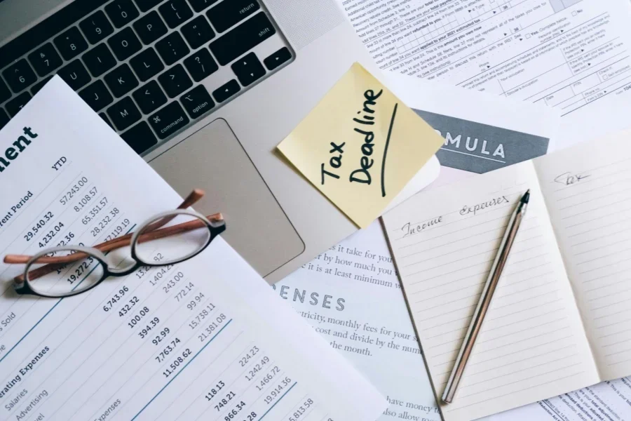 A Notebook and Pen Near the Laptop and Documents on the Table