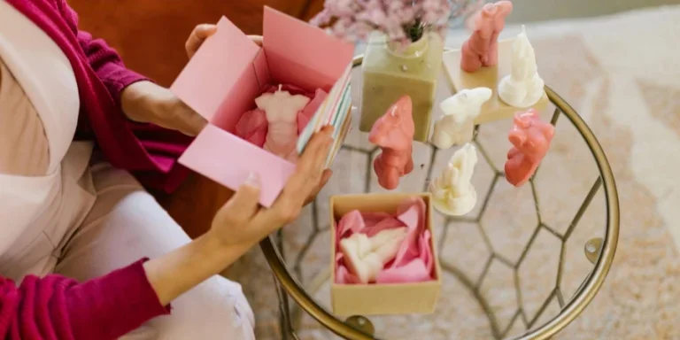 Une femme emballant des bougies au design unique dans une boîte rose
