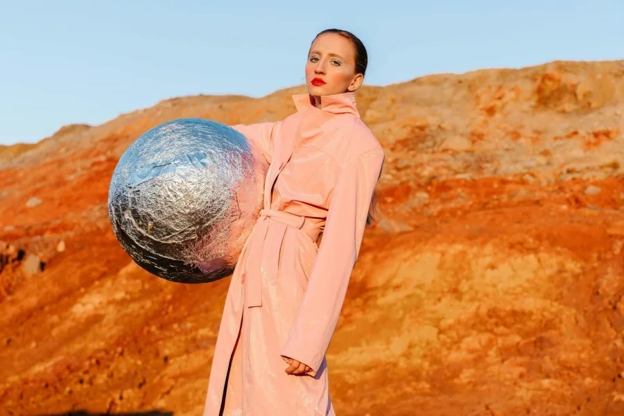 A Woman in Coat Posing with a Silver Ball