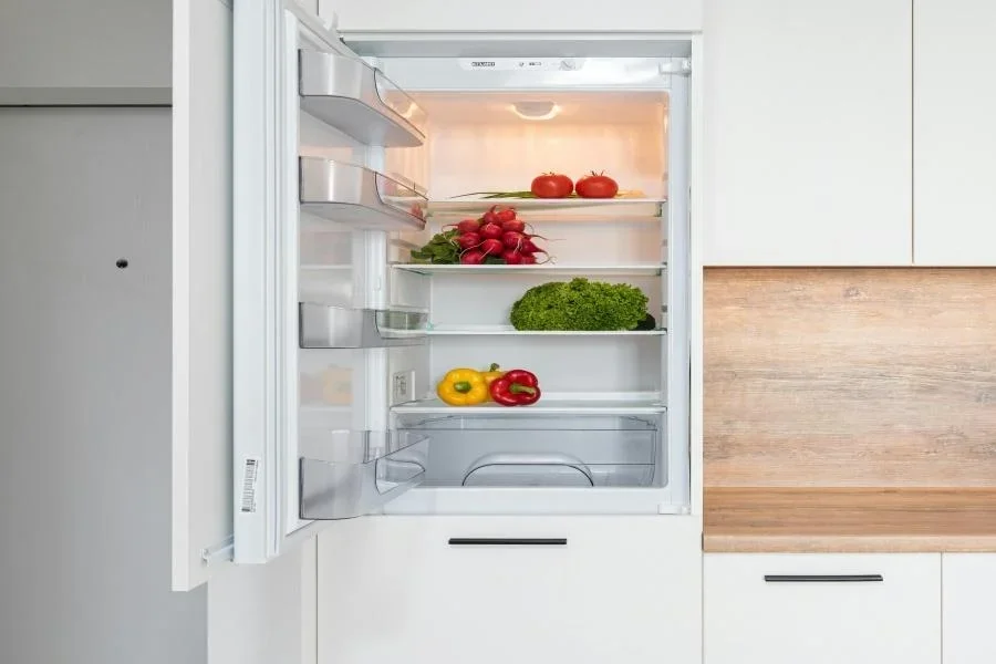 A bottom-freezer fridge in a kitchen with white cabinets