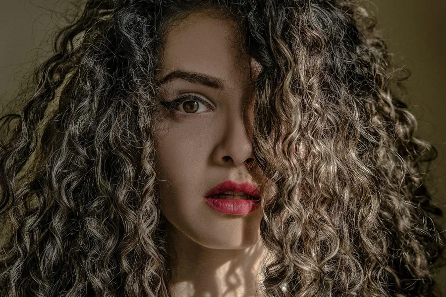 A close up shot of curly hair woman staring in camera.