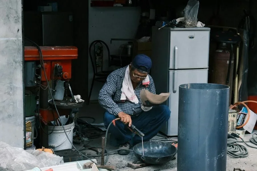 A fridge behind a man working in a garage