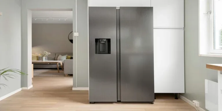 A grey non-plumbed fridge next to a window