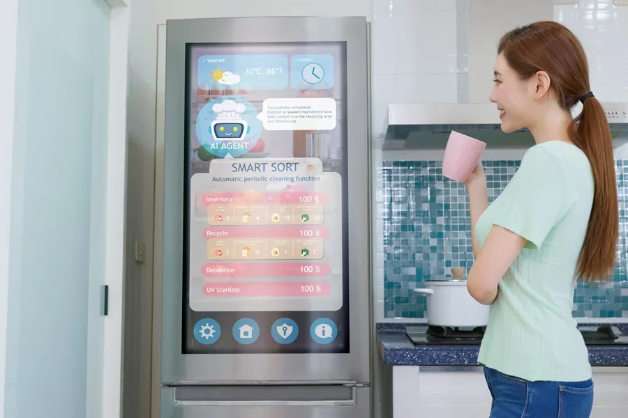 Une dame se tient près d'un réfrigérateur intelligent prêt à recevoir des panneaux de commande.