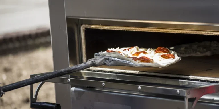 Eine Peperoni-Pizza wird in einen Propangas-Pizzaofen geschoben.