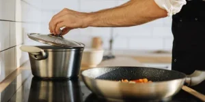A person cooking in a steel pot on an induction stove