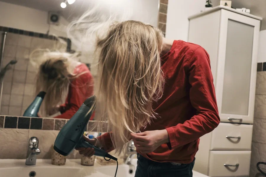 A person holding blow dryer and using upside down blow dry technique.