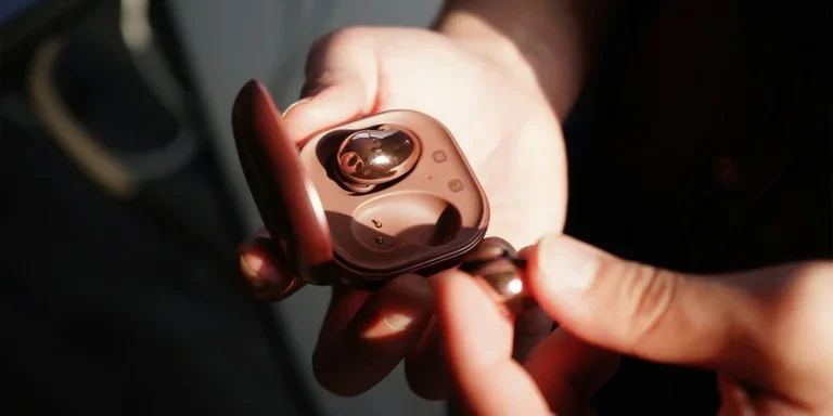 A person holding earbuds and a charging case