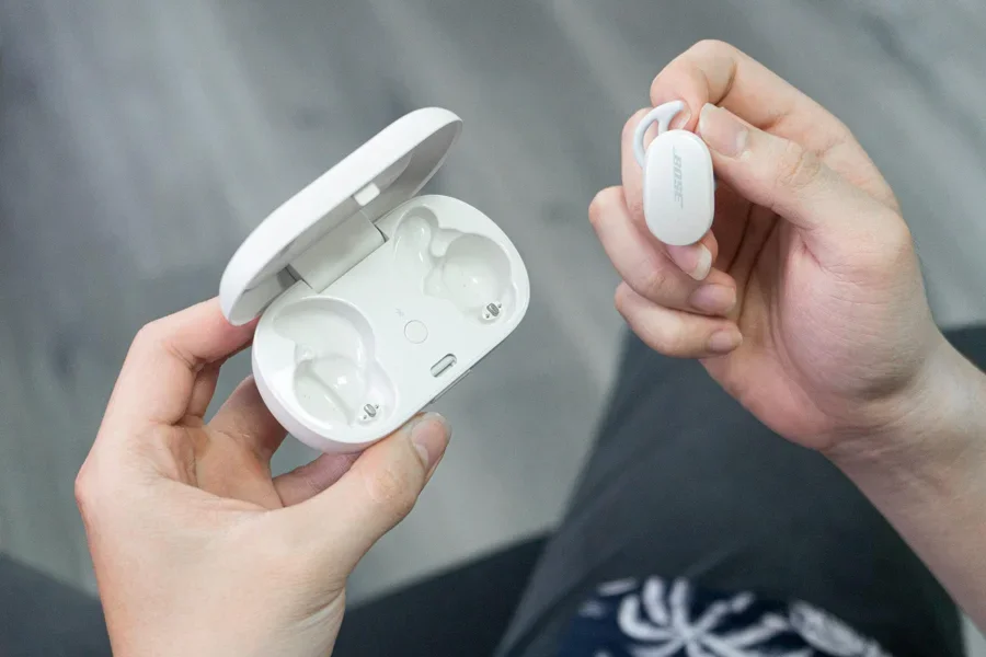 Una persona sosteniendo unos auriculares y un estuche de carga.