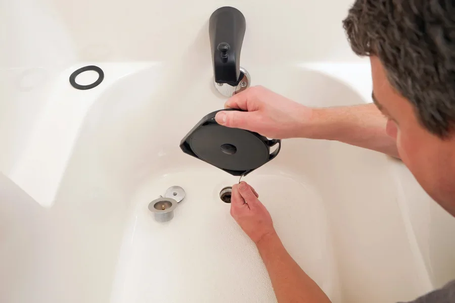 A plumber unclogging a bathtub drain