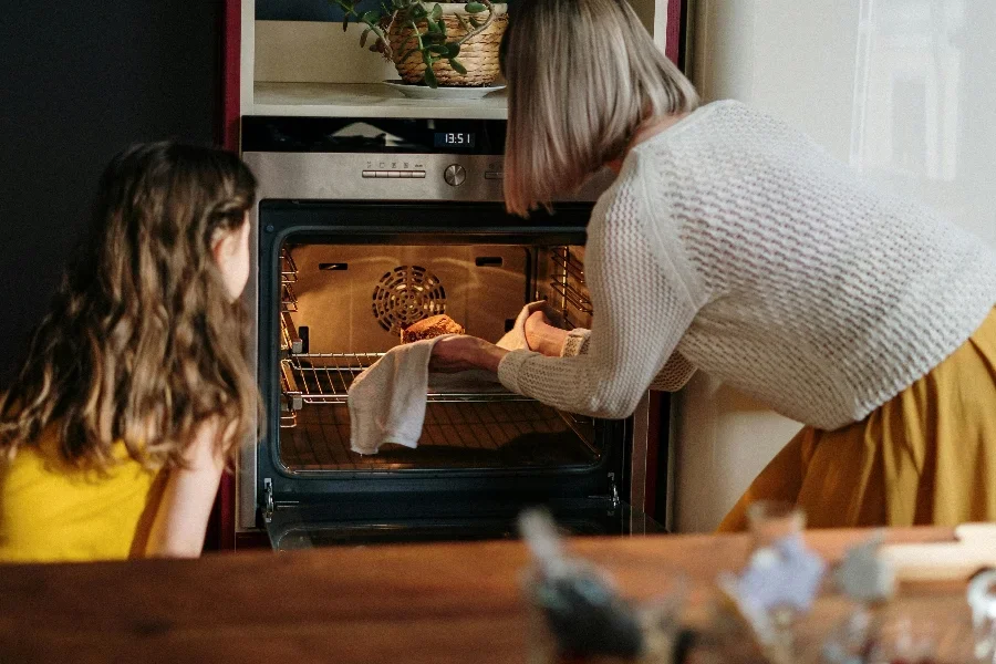 Женщина и ребенок используют духовку-гриль.