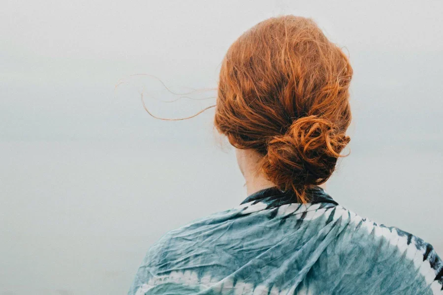 A women in red frizzy hair bun style.