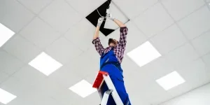 An electrician installing a ceiling panel