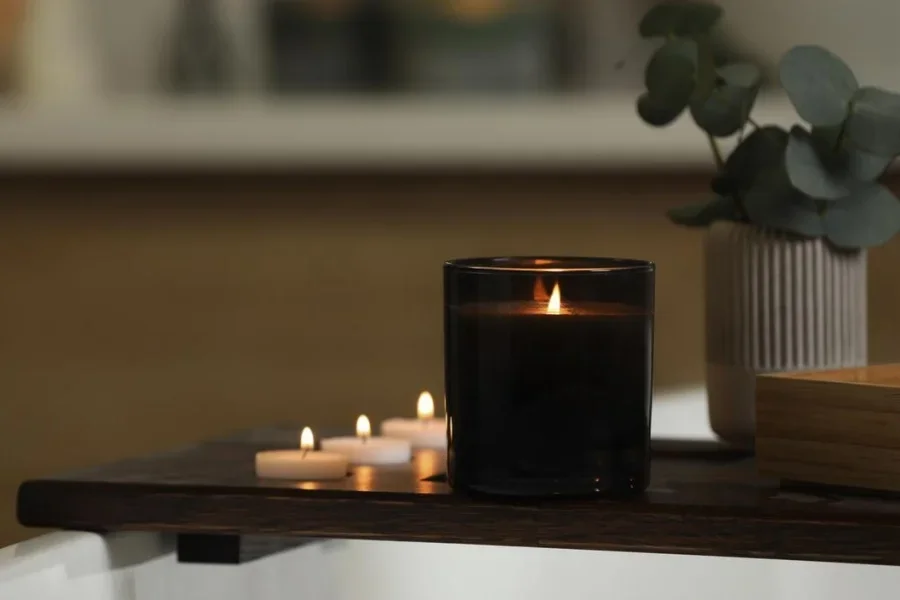 Beautiful burning candles and eucalyptus branches on wooden tray in room, space for text