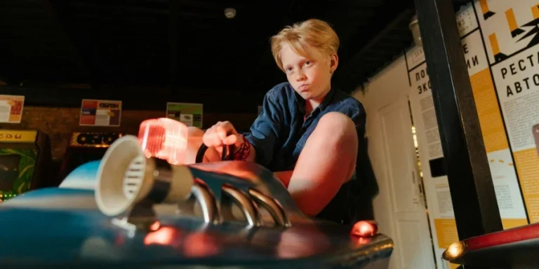 Мальчик в сине-красной рубашке-поло держит белую керамическую кружку