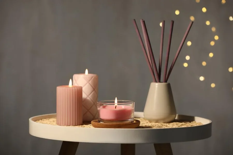 Burning candles and weed diffuser on table against grey background