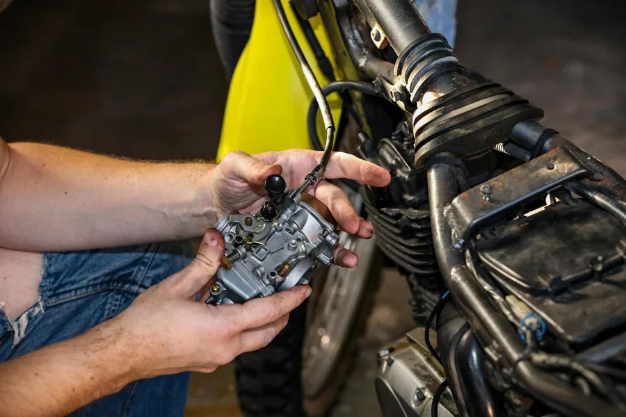 Close-up of a mechanic's hands fixing a motorcycle carburetor