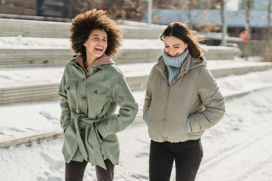 Delighted diverse women strolling on snowy city street