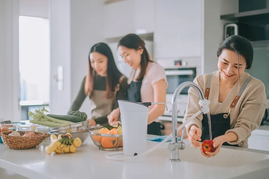 Family cooking and using faucet sink filter to wash apple