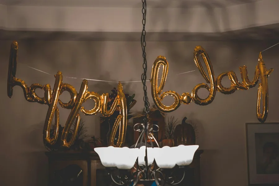 Festliche goldene Ballons mit der Aufschrift „Happy Bday“ hängen im Innenbereich, ideal für Partythemen