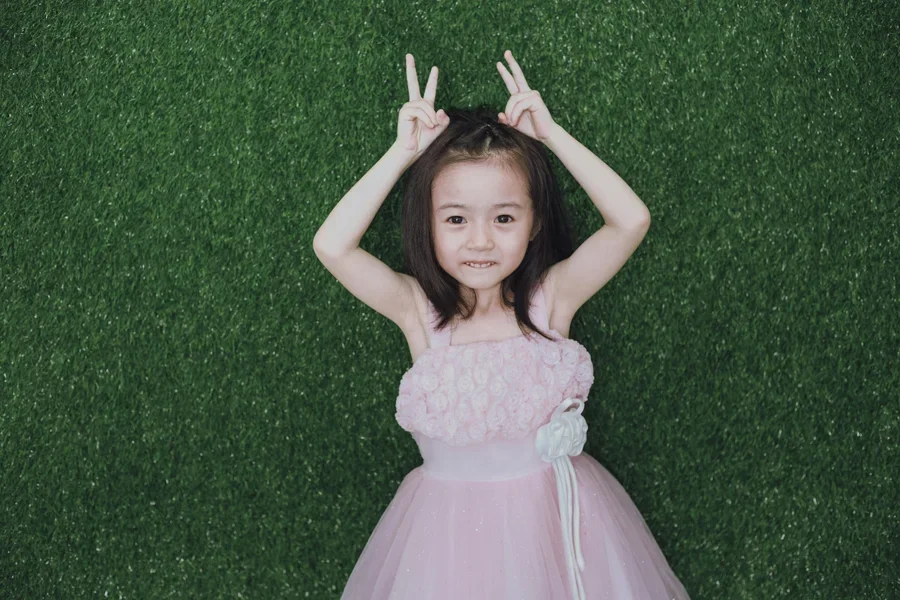 Chica con vestido rosa sobre césped verde