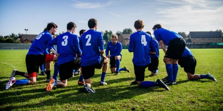 Grupo de deportistas arrodillados en el campo