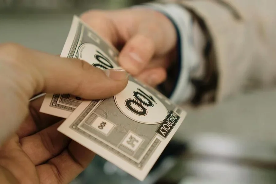 Tangan orang-orang yang menukarkan uang monopoli