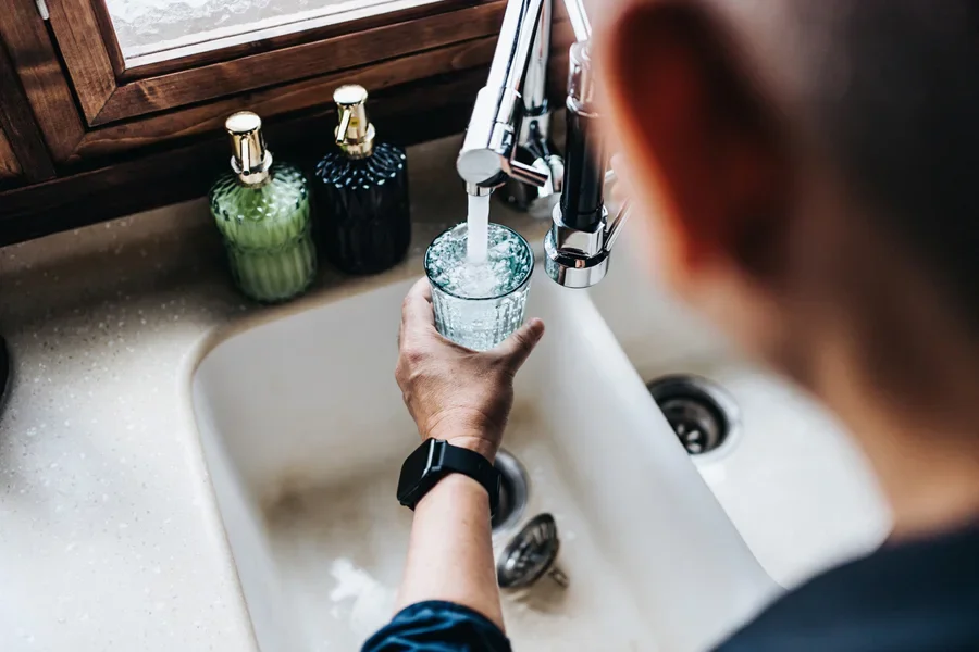 Man getting fresh water from tap in kitchen