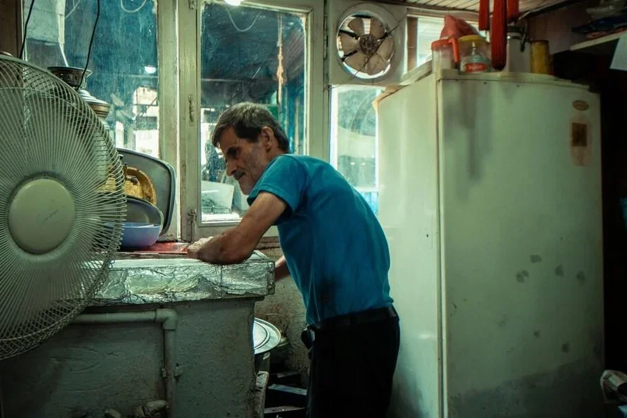 Man in a cluttered space with a white fridge