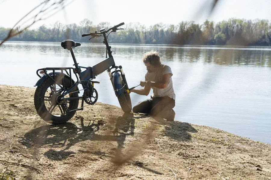Pria menggunakan pompa sepeda listrik pada sepeda listrik saat hari di pantai