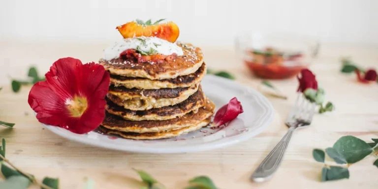 Pancakes on a plate decorated using red flower.