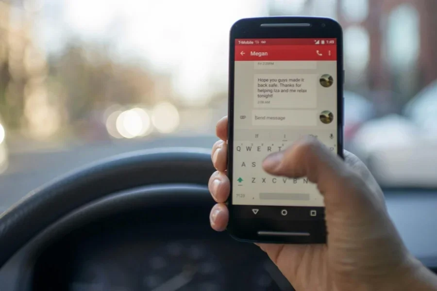 A person sitting inside a car turns on a black Android smartphone