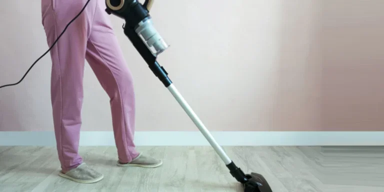 Person reinigt Teppich mit Standstaubsauger