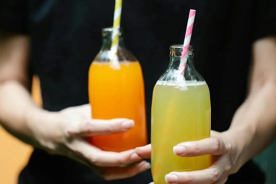 Persona sosteniendo dos botellas de jugo de vidrio