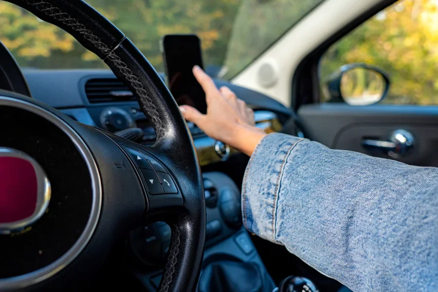 Person reaching for phone mounted in car
