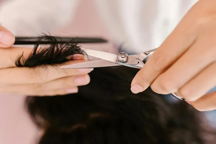 Человек, подстригающий волосы ножницами