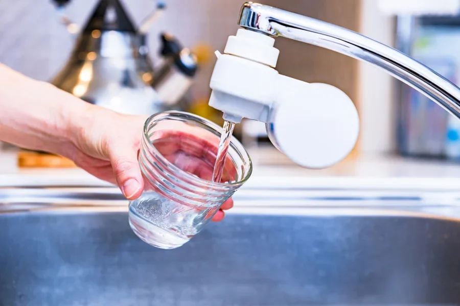 Person using faucet-mounted sink filter to get clean water