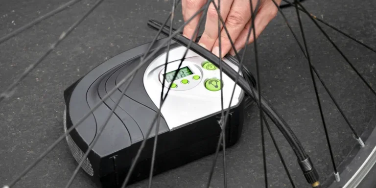 Человек, использующий портативный электрический воздушный насос для накачки шины велосипеда