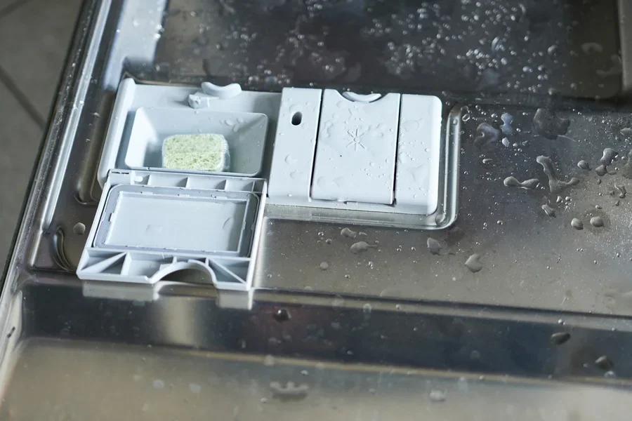 Dispenser bantuan bilas dengan penutup tertutup di dalam mesin pencuci piring basah