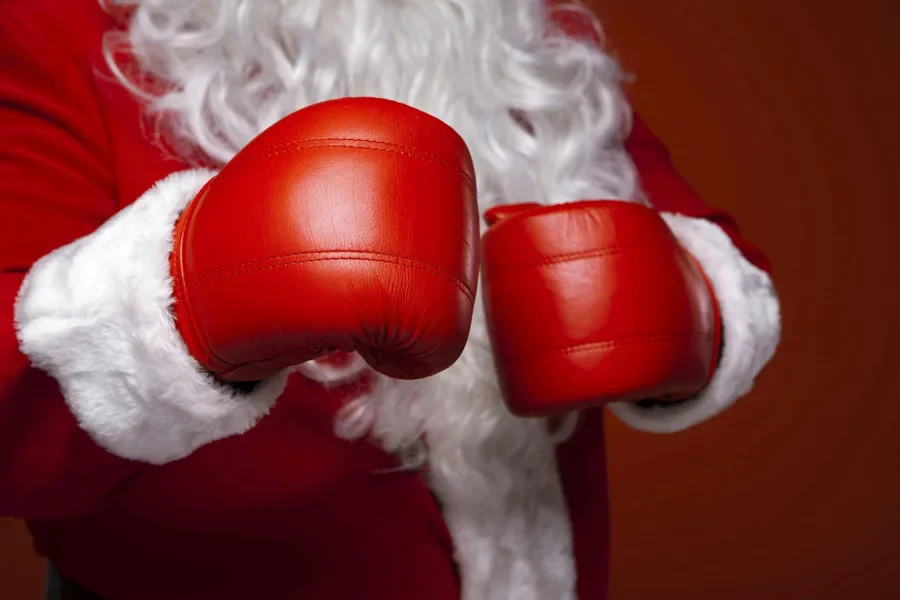 Papá Noel con guantes de boxeo rojos, listo para las fiestas. Primer plano del disfraz y los guantes.