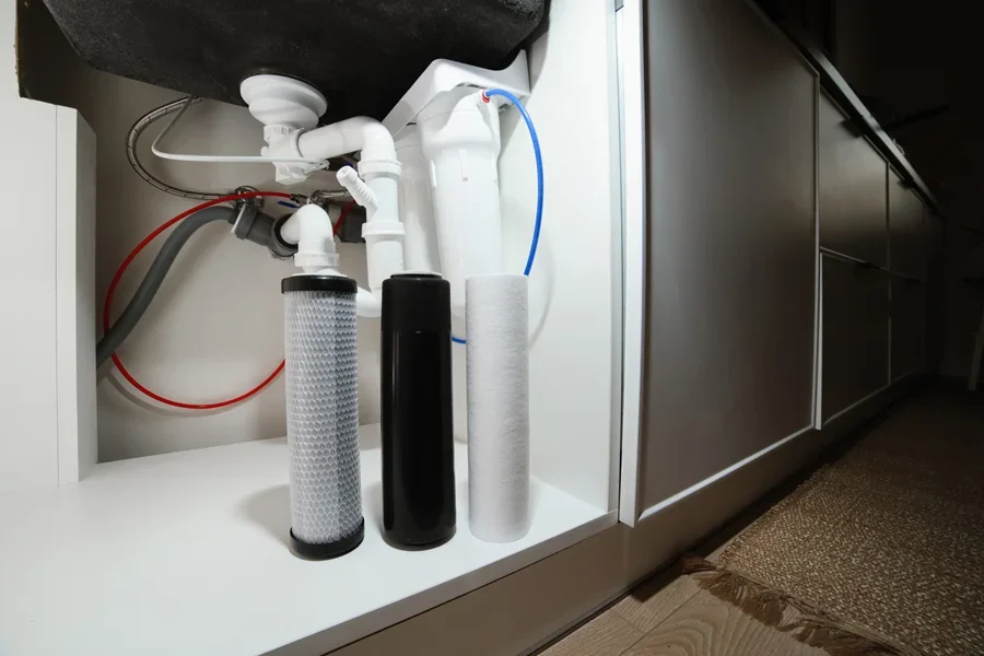 Set of water filters in front of pipes under sink