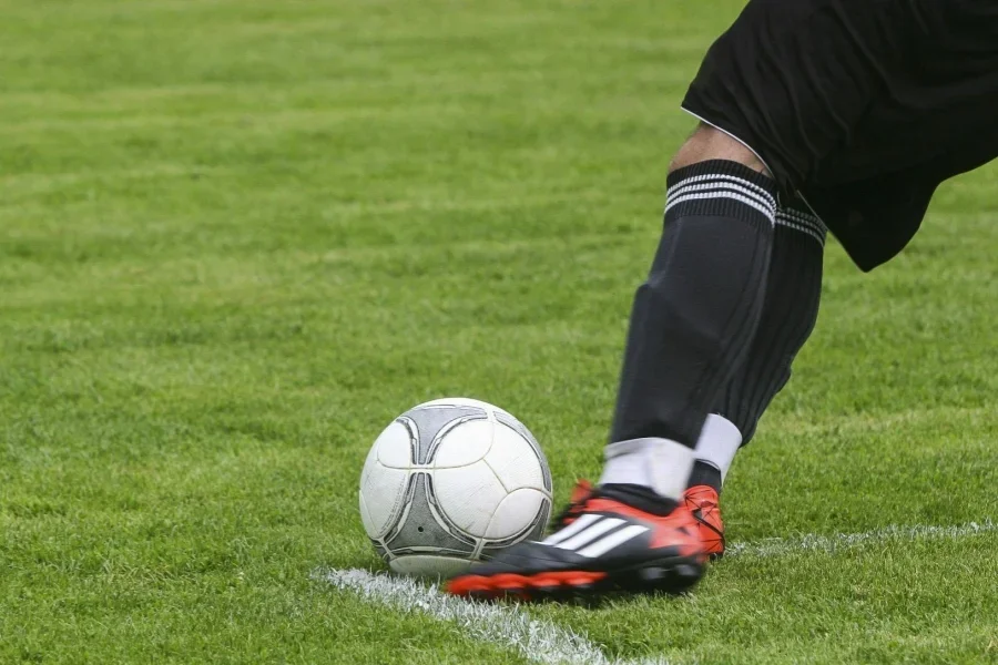 Jugador de fútbol patea una pelota de fútbol blanca y gris en un campo de césped verde