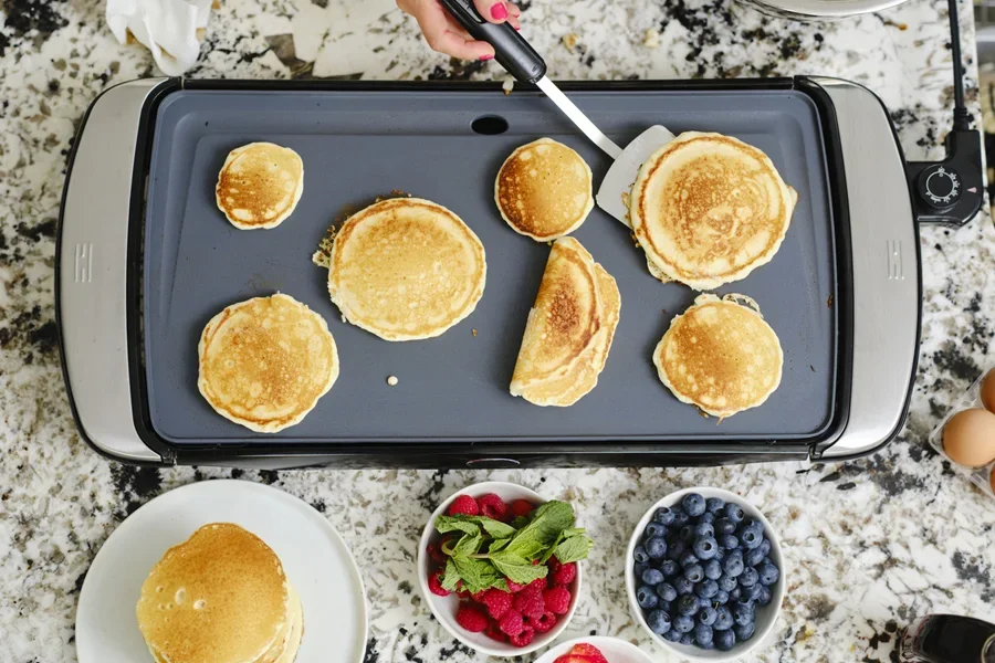 Вид сверху на кухонный стол, на котором выпекается множество блинов.