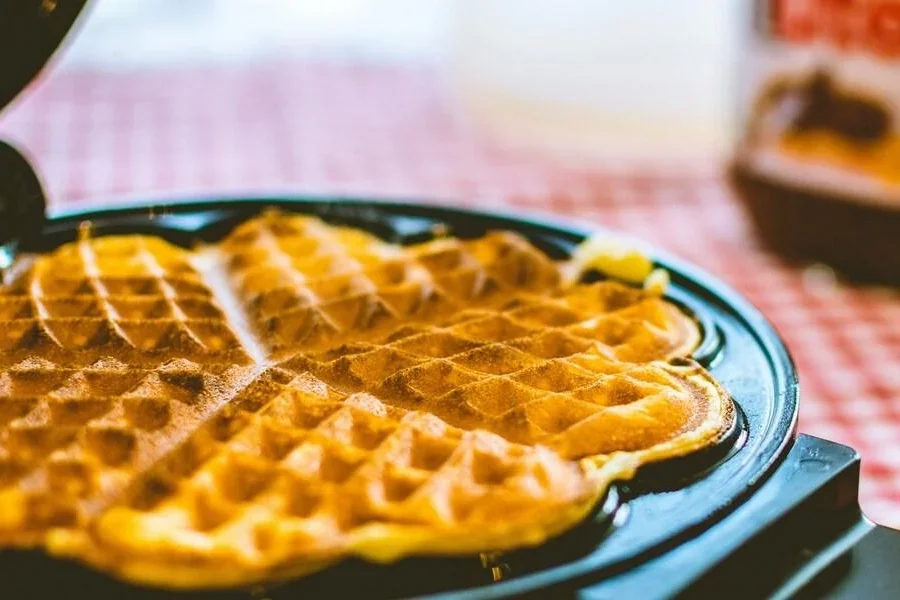 Waffle cooking on a black waffle maker