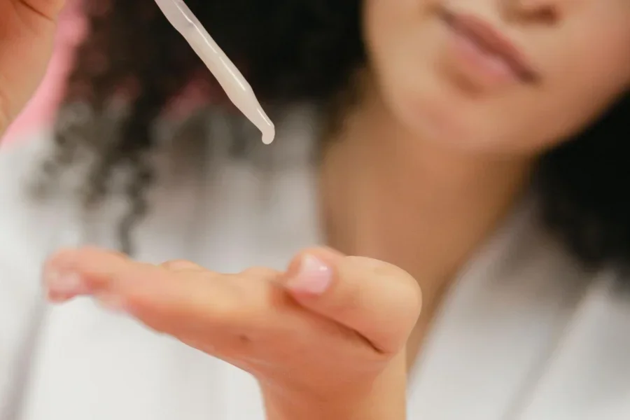 Mujer aplicándose crema en la mano con una pipeta