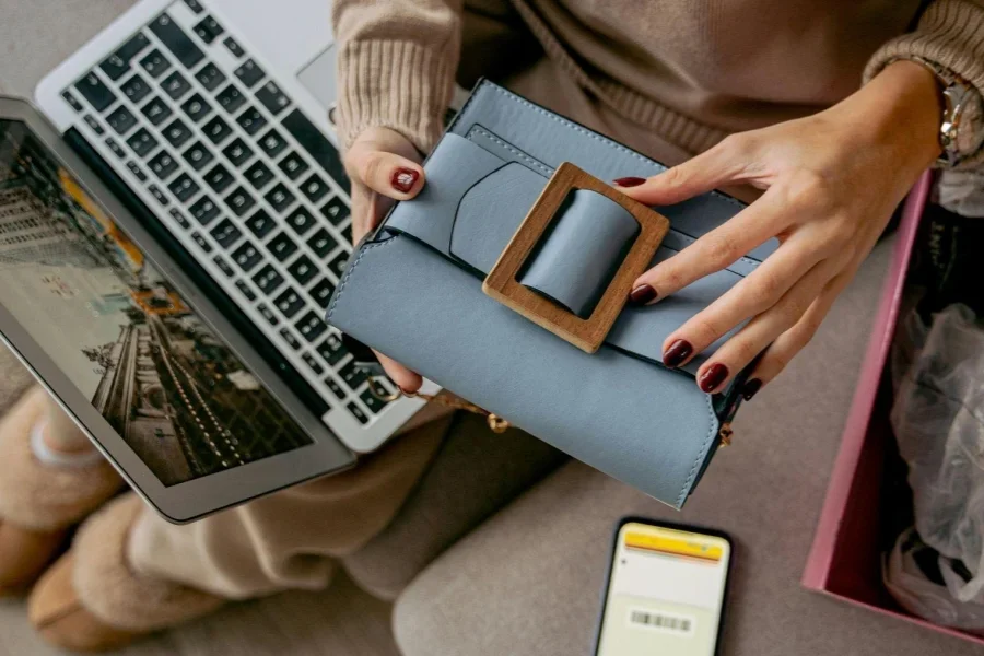 Woman Sitting on a Couch with a Laptop on Her Lap and Holding a New Purchase