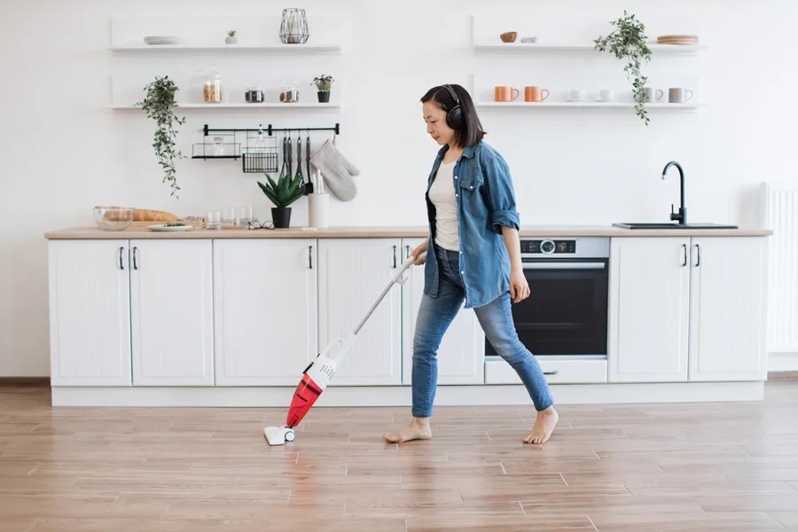Frau putzt Küche mit Standstaubsauger
