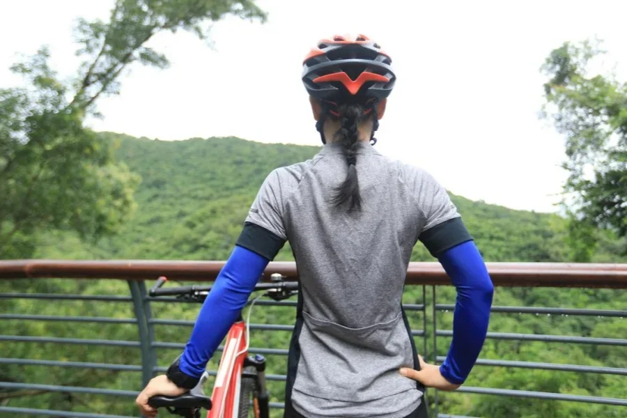 Una mujer ciclista se toma un descanso en un pequeño lugar mientras monta una bicicleta de montaña en una colina de la selva tropical.