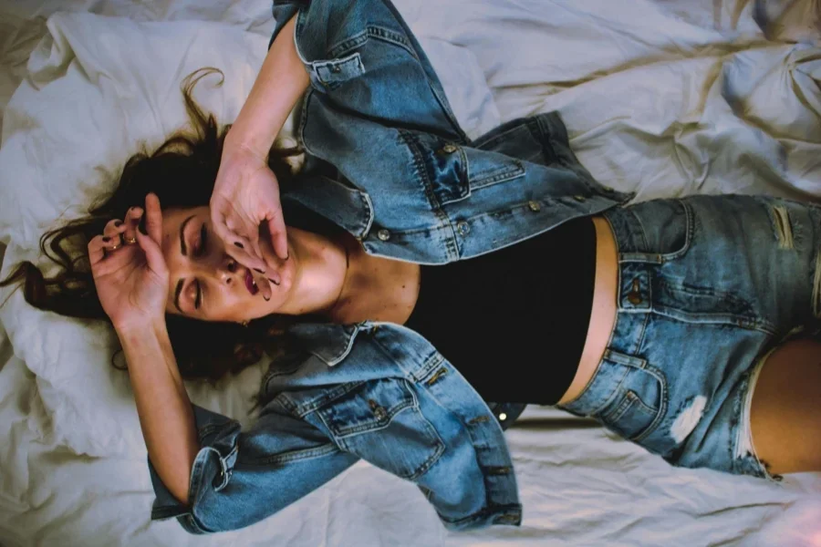 Woman in Blue Denim Jacket Lying Down on Bed