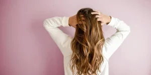 Woman in a white shirt touching her wavy hair